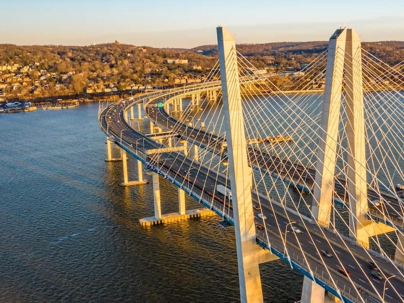 Aerial view of a long cable-stayed bridge. The bridge is curved and has multiple lanes.
