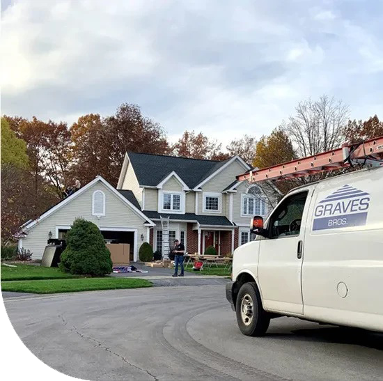 A large house with a car parked in front. The house has two stories.