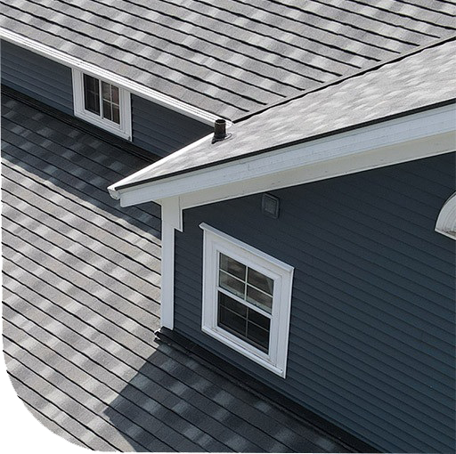 A house with a shingled roof and a window. The image is grainy and black and white.