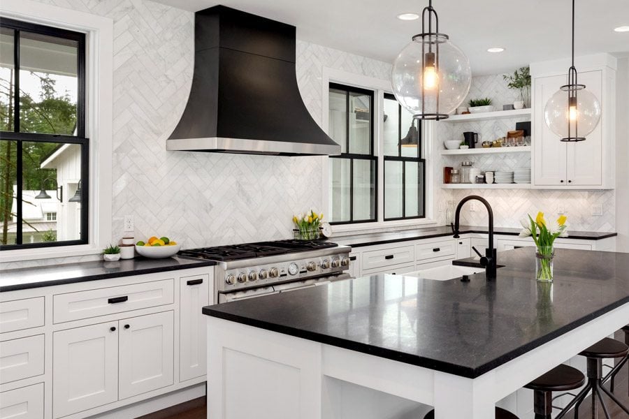 Modern kitchen with black island and white cabinets. The kitchen features a large island with a sink and a black countertop.