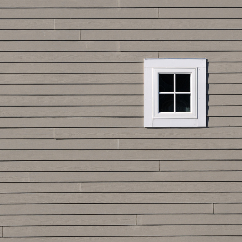 A small window on a dark brick wall. The window has a white frame.