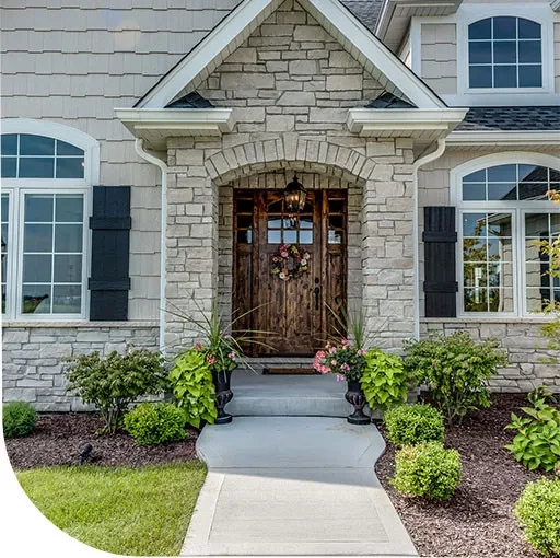 A stone house with a wooden front door and a well-manicured lawn. The house features a charming exterior with a stone facade and a wooden door.