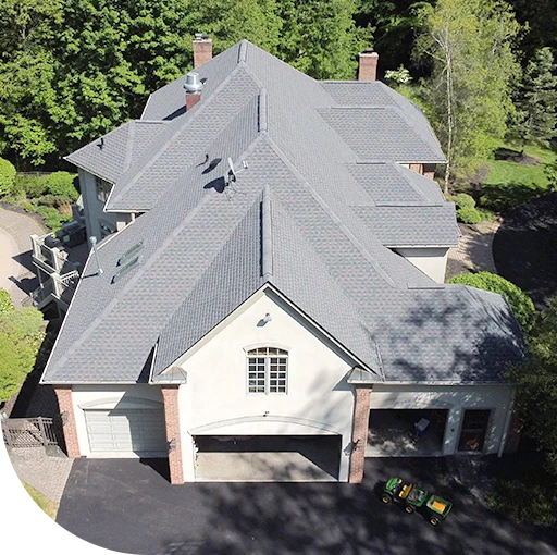 A white house with a large roof and a chimney. The house is surrounded by trees.