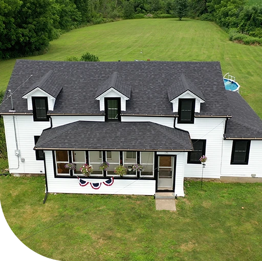 A black and white aerial view of a house. The house has a large porch.