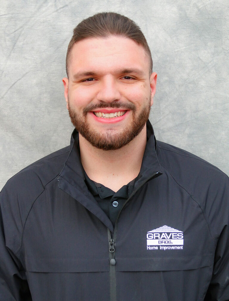 A man with a beard and mustache wearing a black jacket. He is smiling at the camera.