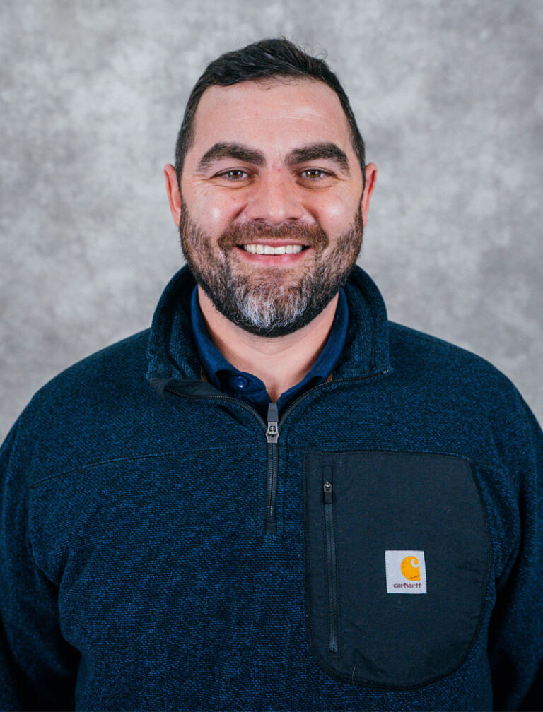 Man with short dark hair and beard wearing blue Carhartt