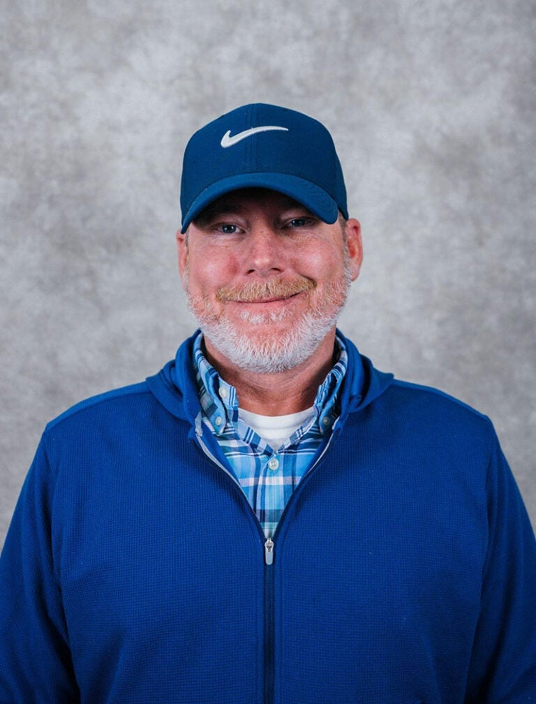 A man with a short beard wearing a blue Nike cap and a blue jacket.