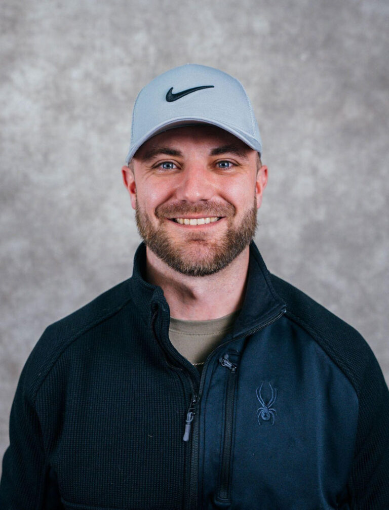 Man wearing a Nike cap and black jacket smiling