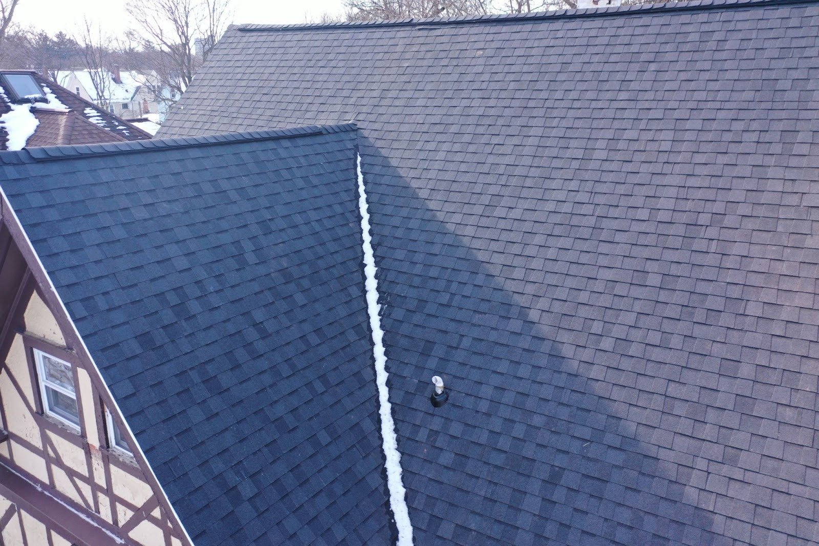 A roof with dark shingles and a white fascia board. The roof is angled and has a gutter system.
