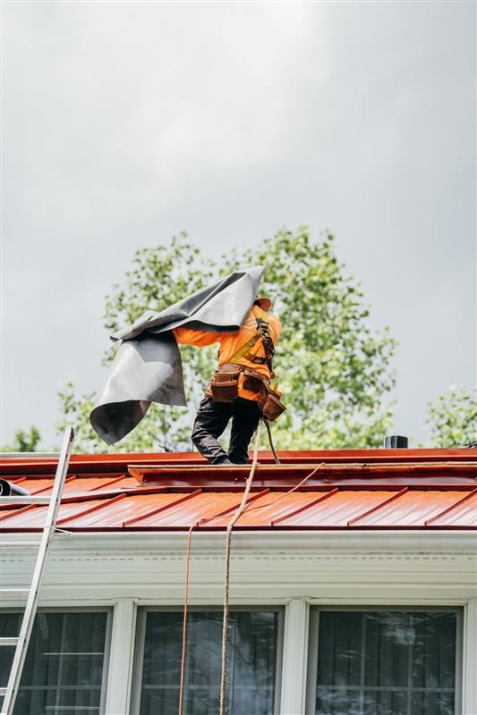 A person in an orange jacket on a roof with a chimney.