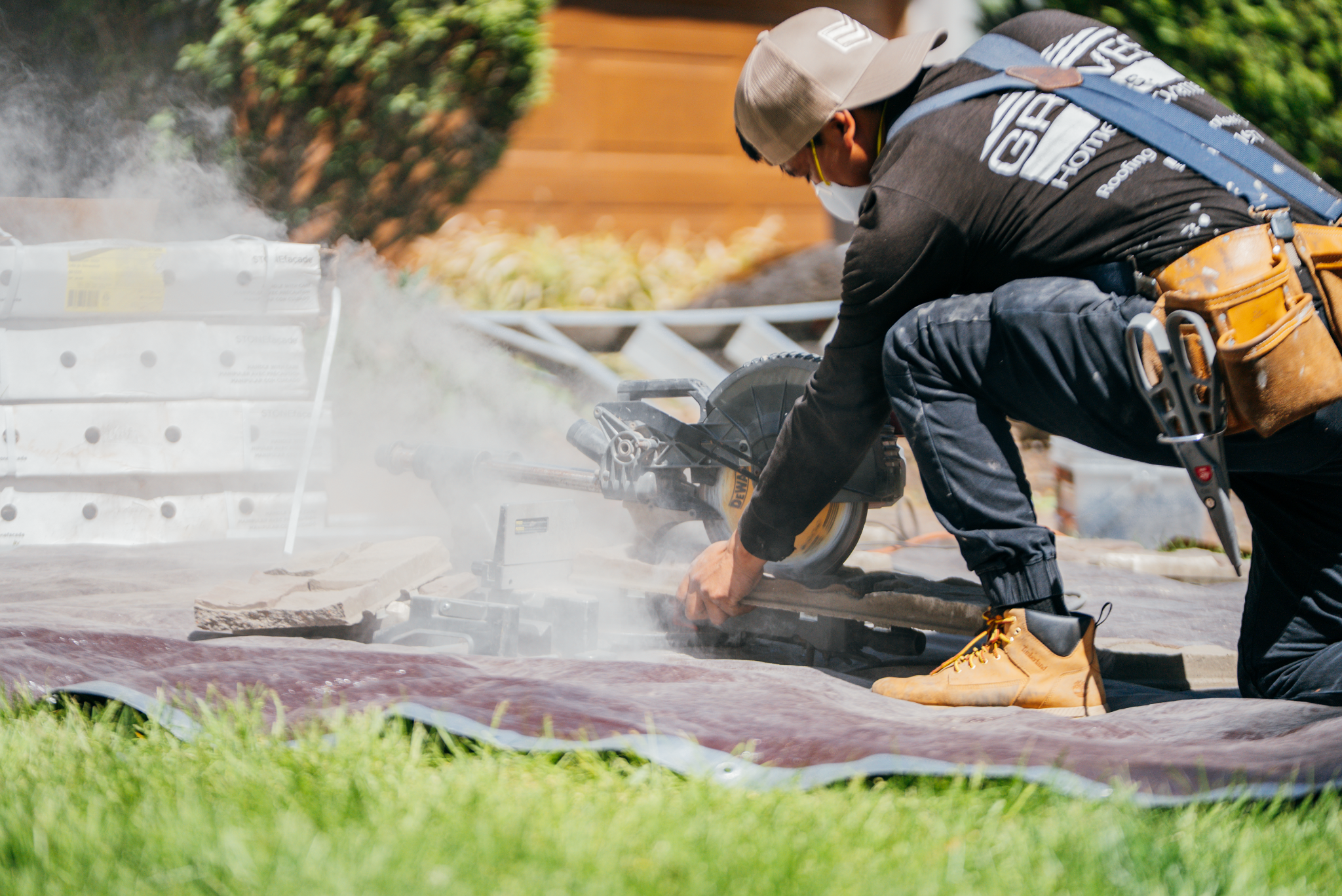 A construction worker cutting roofing material with a power tool.