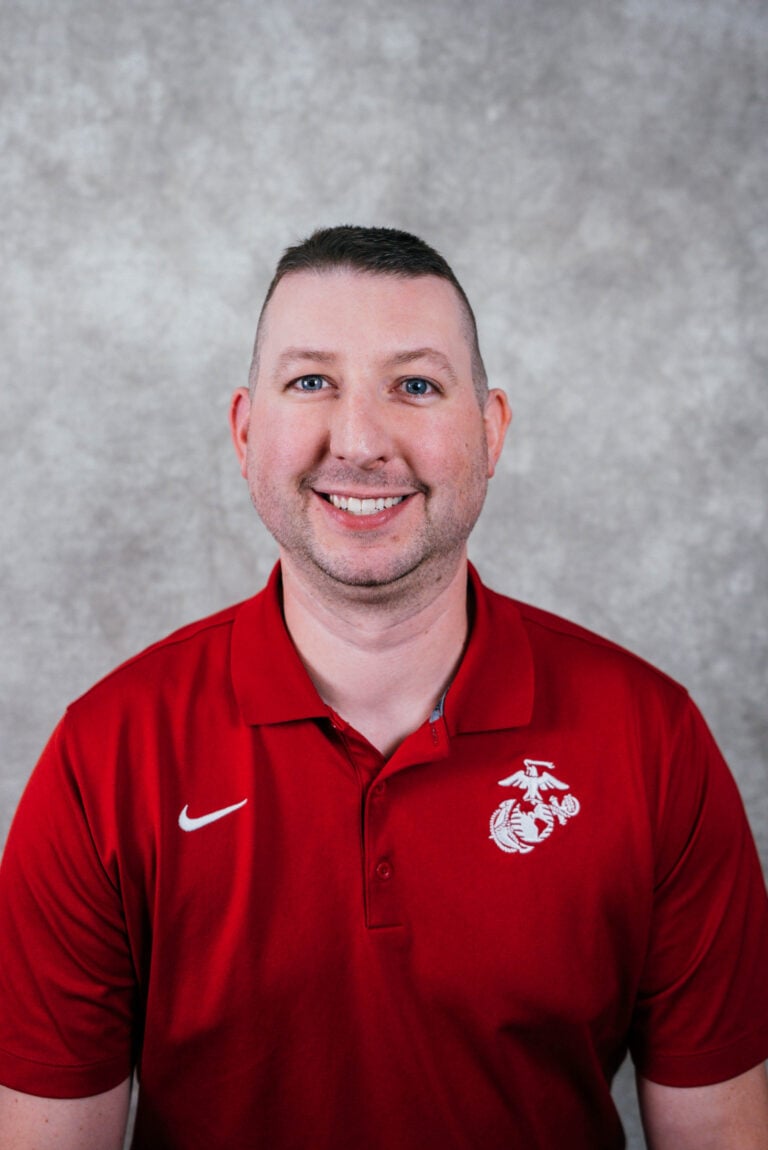 A man wearing a red polo shirt with a white Nike checkmark and Washington State University logo.