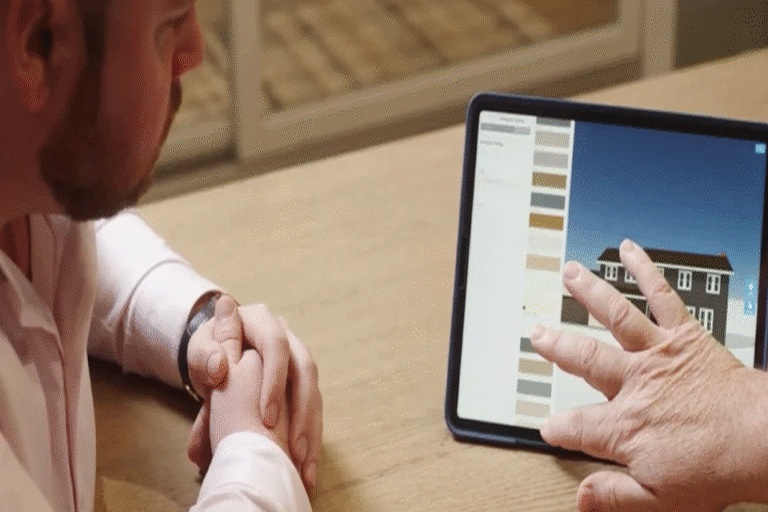 A man reviews architectural plans and color schemes on a tablet while collaborating with a client.