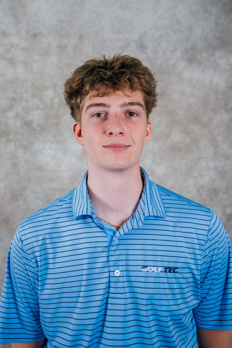A young man with brown hair wearing a blue striped polo shirt, smiling slightly against a neutral background.
