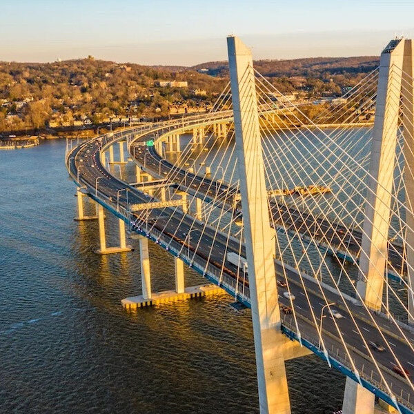 Aerial view of a long cable-stayed bridge. The bridge is curved and has multiple lanes.