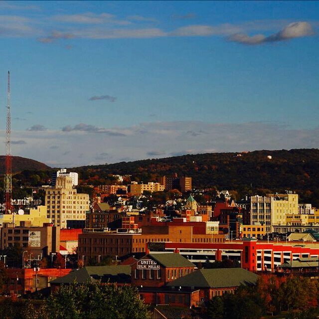 City skyline with buildings. Mountain range in background.