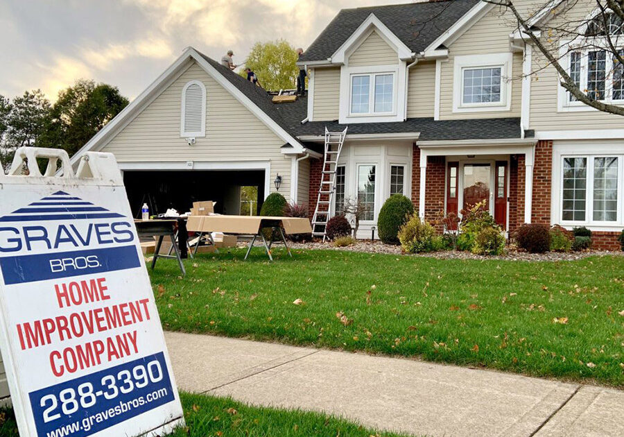 A sign for Graves Bros Home Improvement Company in front of a house. The company offers home improvement services.
