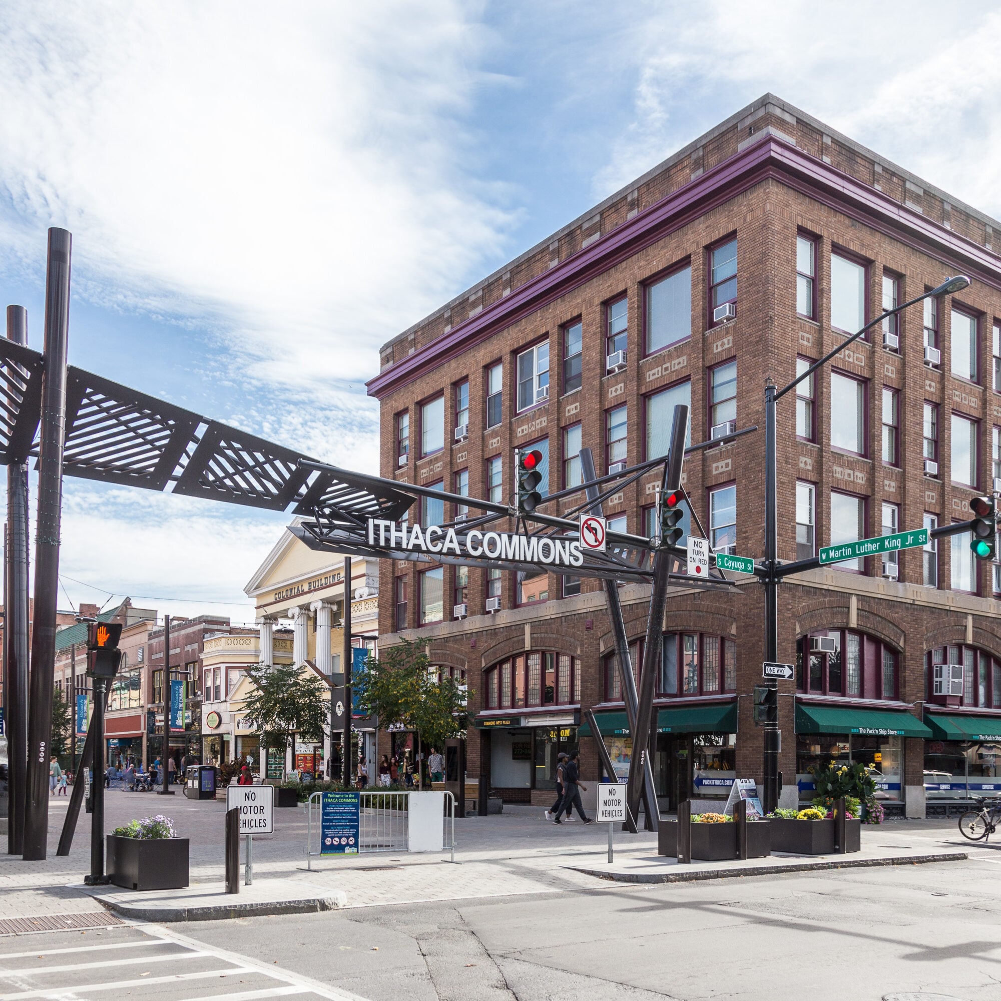 Street view of Ithaca Commons featuring a large metal art installation and a multi-story brick building.