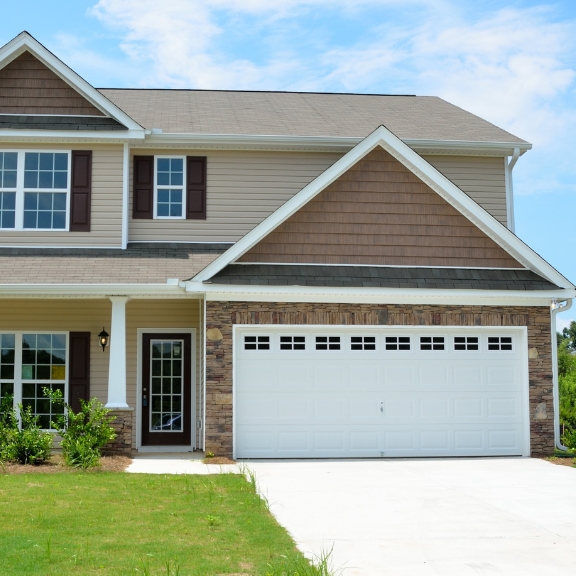 A two-story house with a garage and driveway. The house has a brick exterior